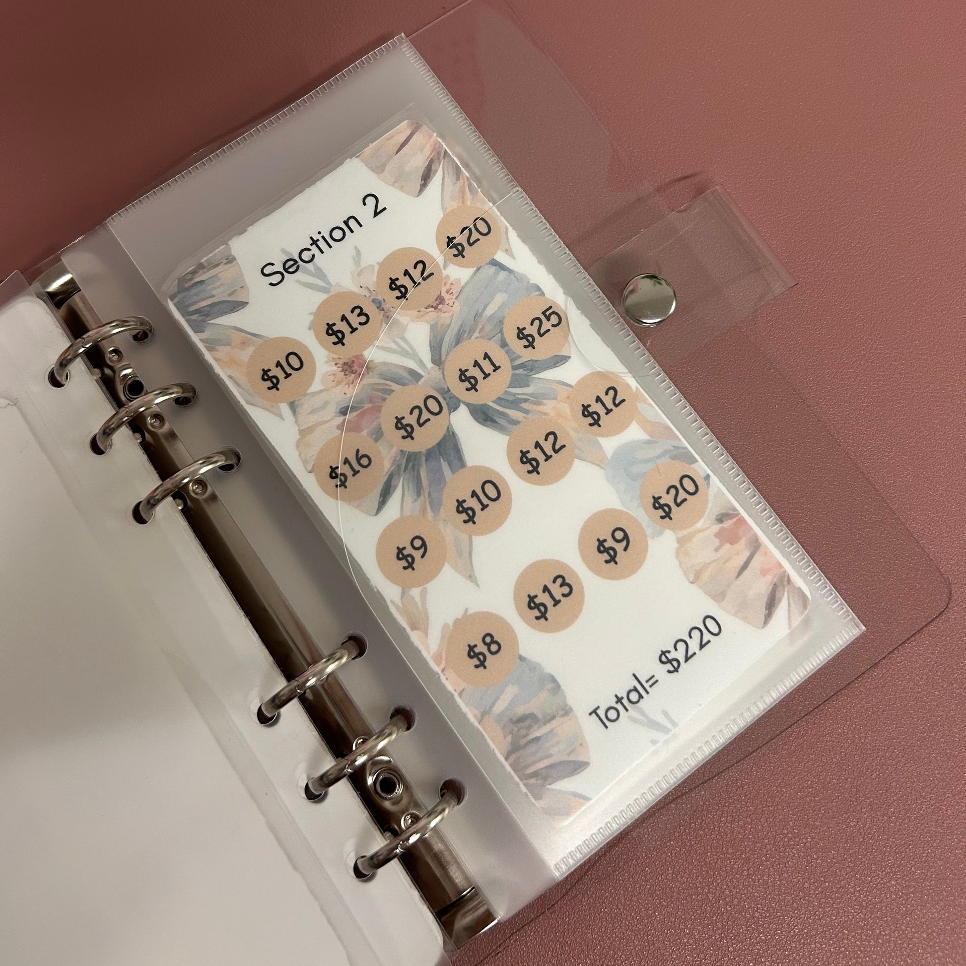 Planner with labeled tabs on a pink surface