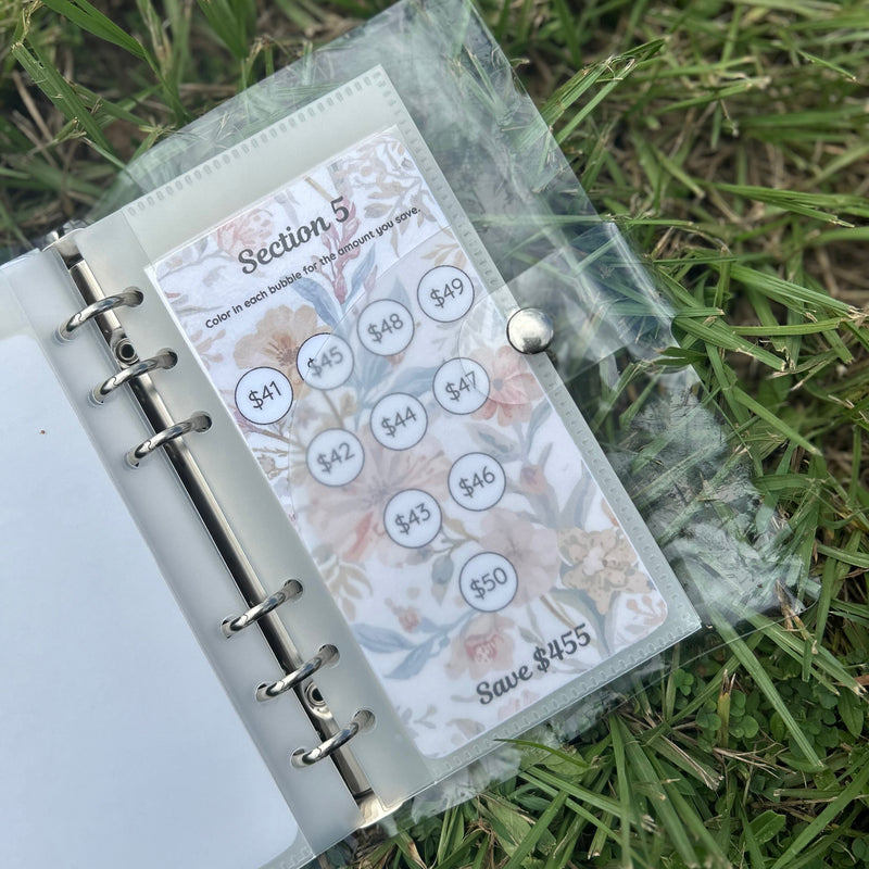 Planner with a clear sleeve showing budget stickers on grass