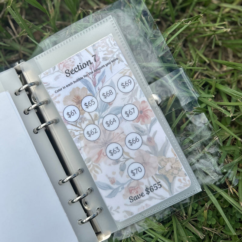 Planner with a floral design on the cover, placed on grass.