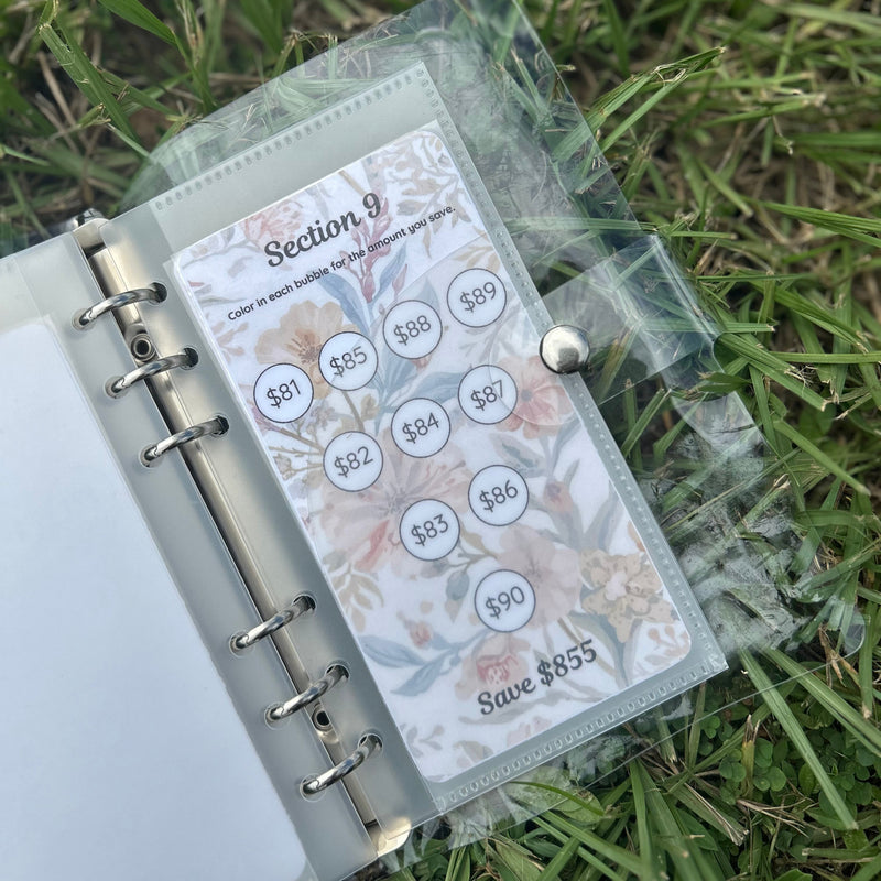 Planner with money-saving stickers on a grass background