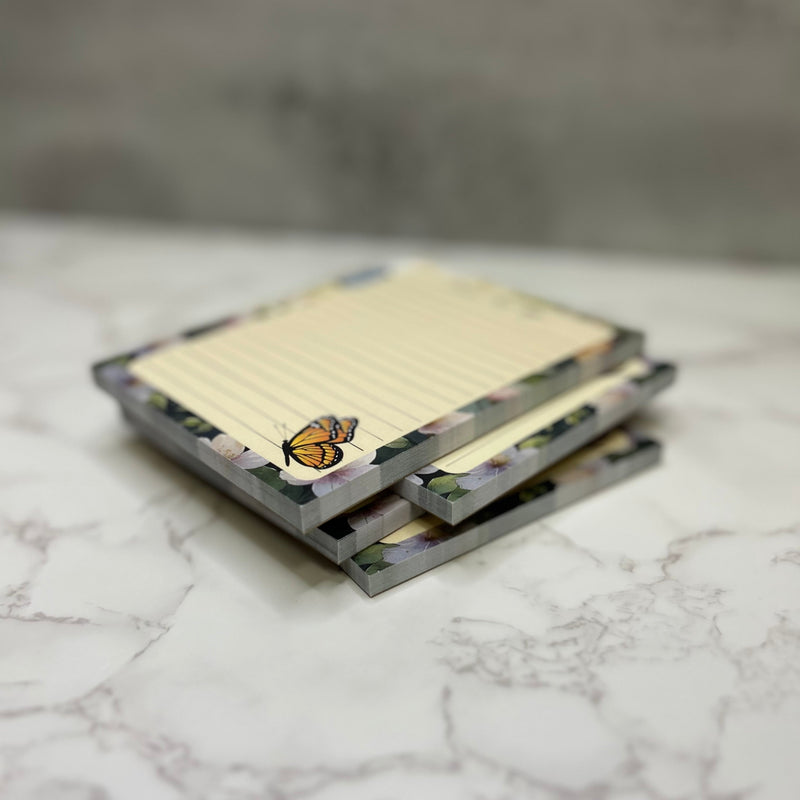 Stack of notebooks with a butterfly design on a marble surface
