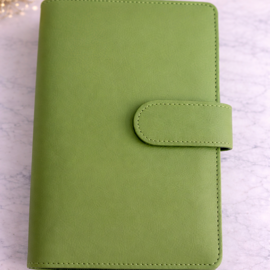 Green planner on a light gray surface with blurred lights in the background