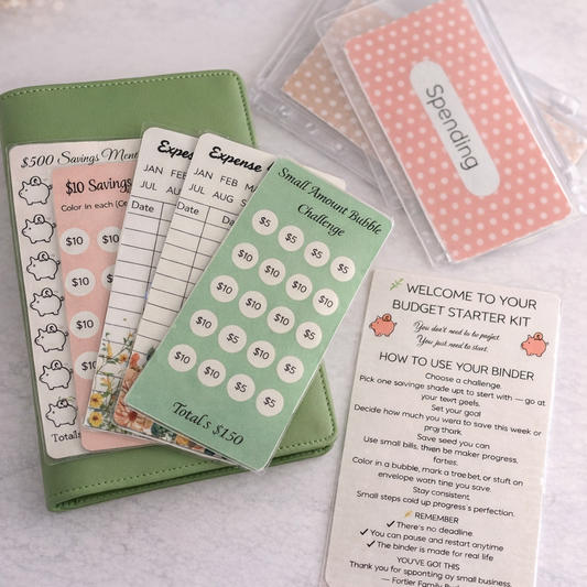 Budgeting tools including a green notebook, cards, and a card holder on a light surface.