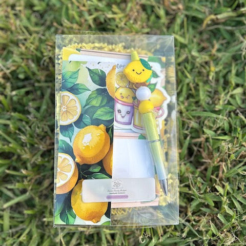 Set of stationery items with lemon-themed design on grass