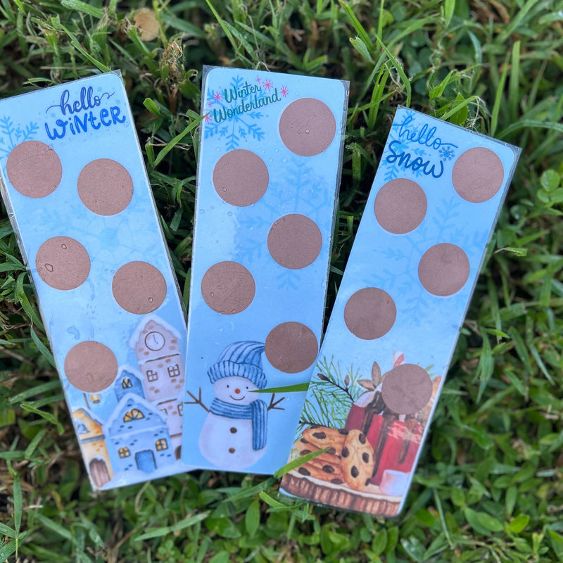 Three packages of stickers with winter-themed designs on a grass background